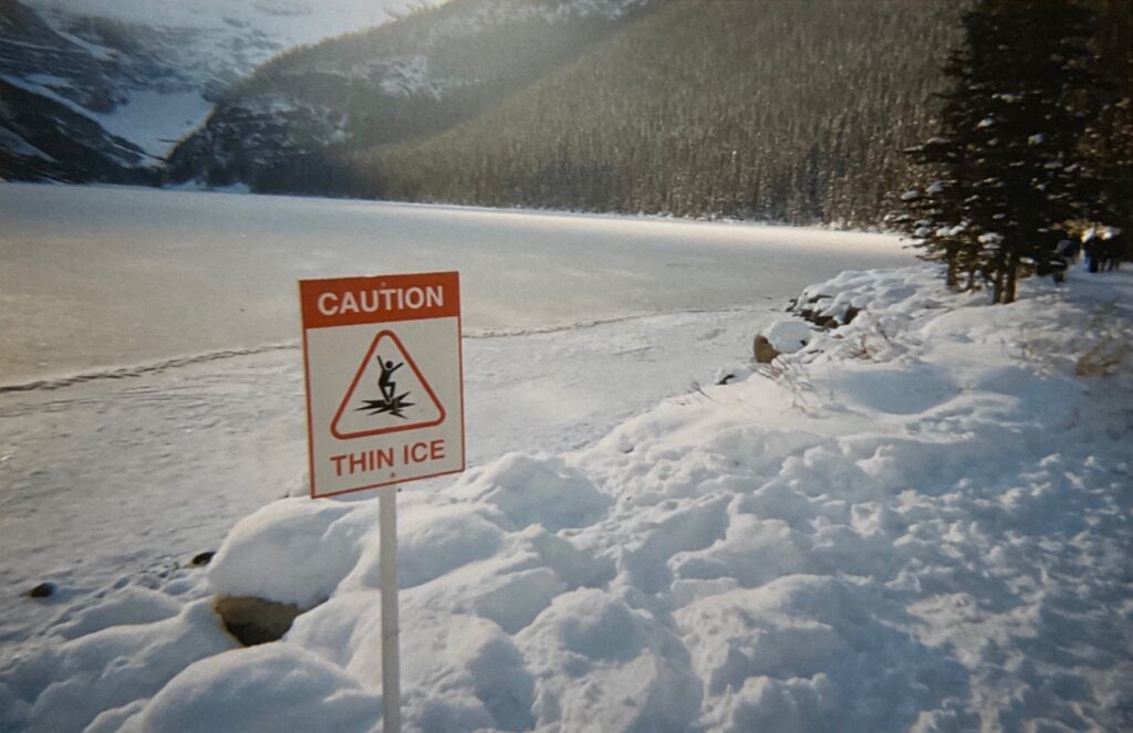 Caution sign on the shore of the lake; it says the ice is thin